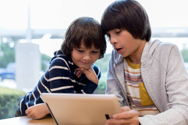 istock Middle school boy teaches brother how to use laptop 1193583434
