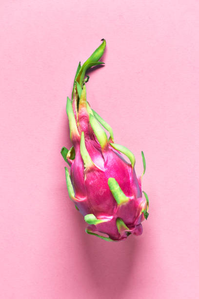 istock Creative flat layout with fresh organic pink, white and green dragonfruit (pitaya or pitahaya) on pink paper background. Trendy top view, flat lay of the whole fresh ripe healthy exotic fruit. 1193585700