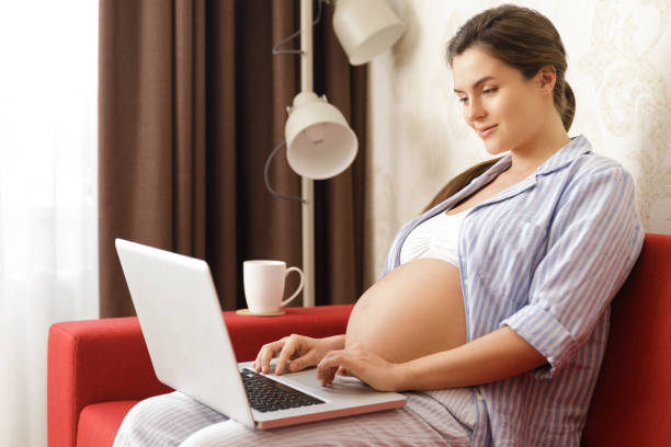 istock Young pregnant woman sitting with a laptop computer 1193586209