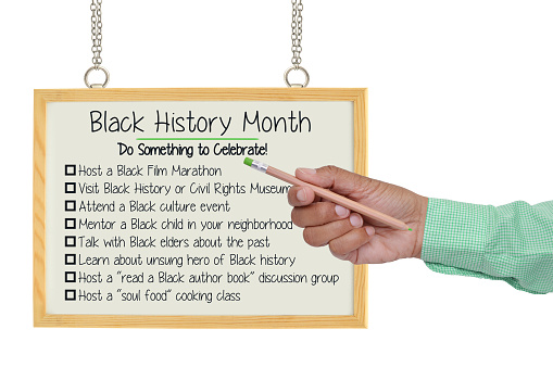 Hand pointing to Black History Month white board with list of activities to do white background