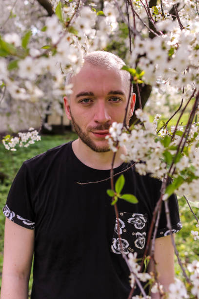 istock A young bearded man walking around Kolomenskoye park. An attractive guy looking through blooming cherry tree to camera. 1193599220