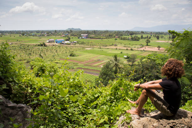 istock Male tourist looking at green rice paddy fields from high angle, Cambodia 1193601905