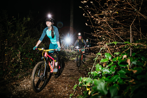 An all female mountain bike team enjoys a ride on some forest trails at night, equipped with bright head lamps and bike lights.   Shot in Washington State on the Olympic Peninsula.