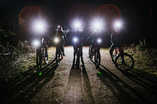 Silhouette of Women's Mountain Biking Club on Night Ride An all female mountain bike team enjoys a ride on some forest trails at night, equipped with bright head lamps and bike lights.   Shot in Washington State on the Olympic Peninsula. bicycle light photos stock pictures, royalty-free photos & images