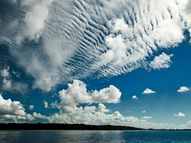 A spectacular inspirational brightly coloured cloudy sea water tropical seascape featuring  white Altocumulus cloud formation (AKA. Mackerel Sky) in a blue sky with ocean water reflections. Australia.
