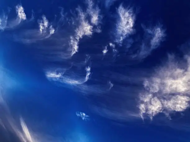 A spectacular inspirational brightly coloured atmospheric cloudy sky cloudscape featuring streaky cirrus clouds in a cobalt blue sky. Tin Can Bay, Australia.