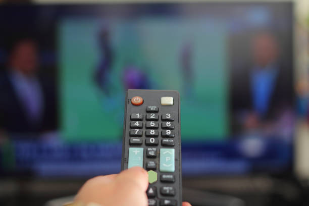 uma pessoa com um controle remoto da tv controla o controle remoto para mudar de canal para assistir a programas de tv. - entertainment home interior electronics industry remote control - fotografias e filmes do acervo