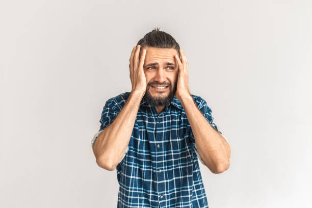 istock Freestyle. Guy in checkered shirt standing isolated on white holding head concerned 1193614297
