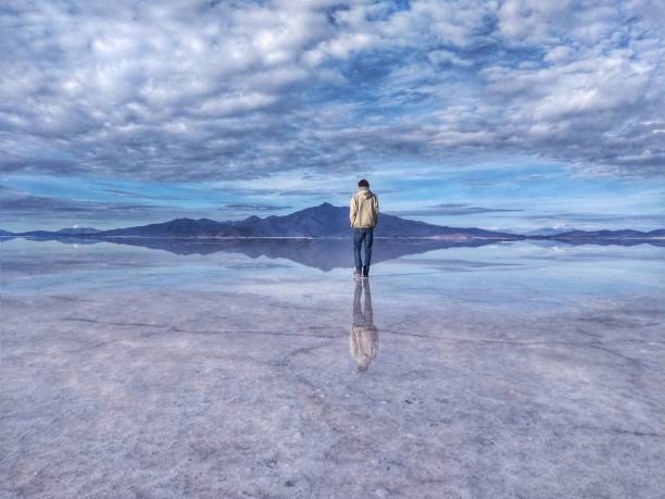 homem em salar de uyuni, o maior sal plana do mundo, bolívia, américa do sul - lago reflection - fotografias e filmes do acervo