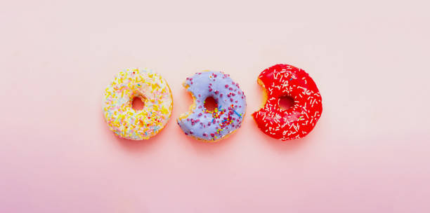 istock Bitten colored donuts  with colorful sprinkles on pink background. Copy space 1193621051
