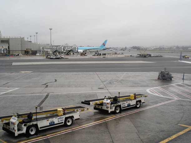 Boston Logan, November 12th, 2019: Two airport conveyor trucks in the foreground with a jet in the background.