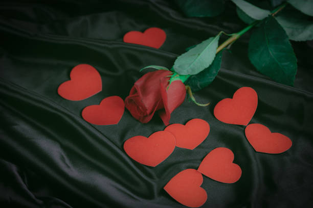 istock red rose and hearts on black silk background 1193635860