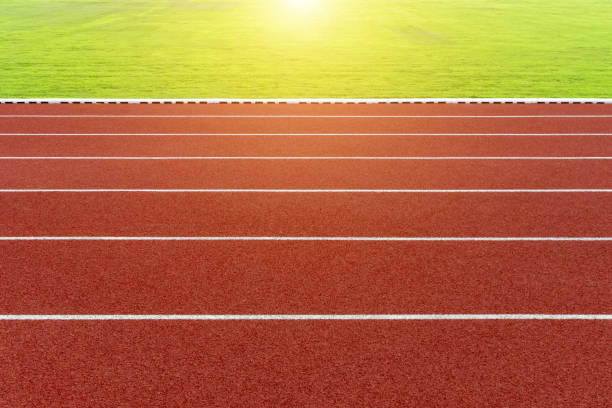istock Red treadmill at the stadium with green grass and sunlight. 1193643138