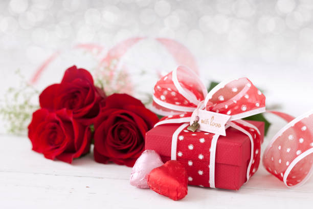 Valentine's Day Gift with Red Roses and Chocolates Valentine's Day Gift with Red Roses and Chocolates on a defocused lights background heart shape valentines day chocolate candy food stock pictures, royalty-free photos & images