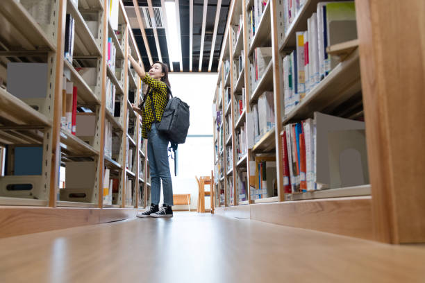 istock Beautiful woman choosing book in the library 1193650893