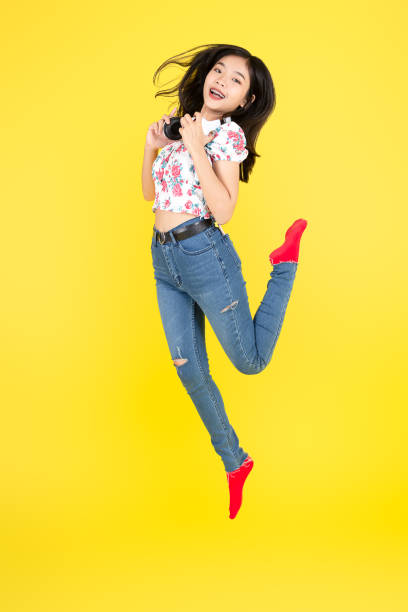 istock Happy Asian woman using headphone dancing and jumping on yellow background. 1193653305