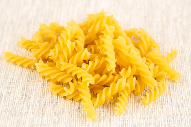 The heap of fusilli pasta on the fabric background.