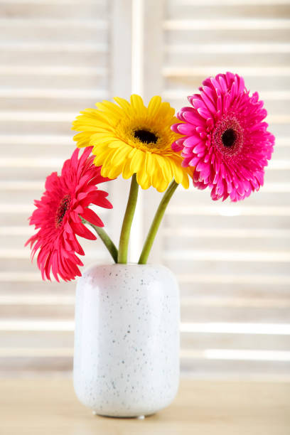 istock Ceramic vase with gerbera flowers on wooden background 1193662004