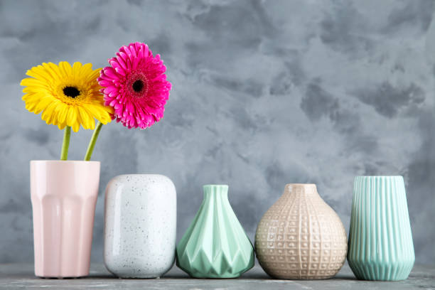 istock Different ceramic vases with gerbera flowers on gray background 1193662454