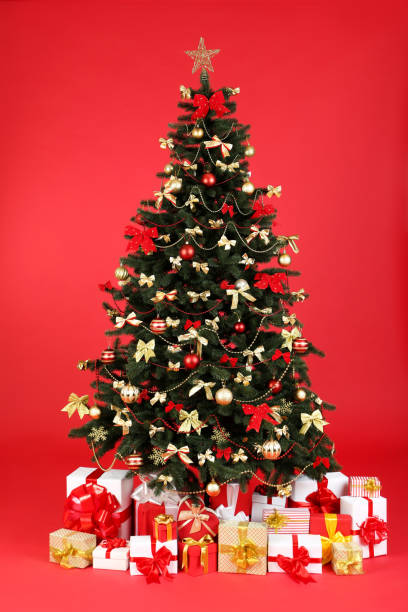 istock Christmas fir tree with ornaments and gift boxes on red background 1193662923