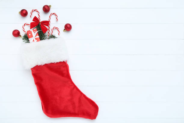 istock Red stocking with christmas ornaments on white wooden table 1193666549