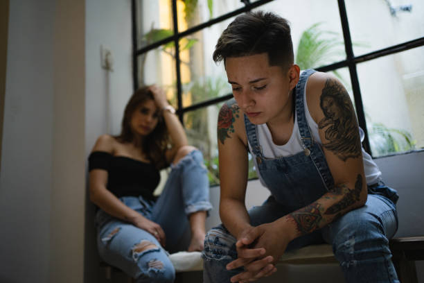 Couple with relationship difficulties Lesbian couple looking upset after having an argument at home. sad gay stock pictures, royalty-free photos & images