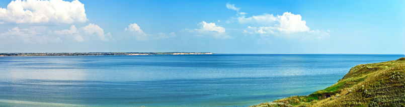 Panoramic view of the sea bay with green hills; this image was made from three photos