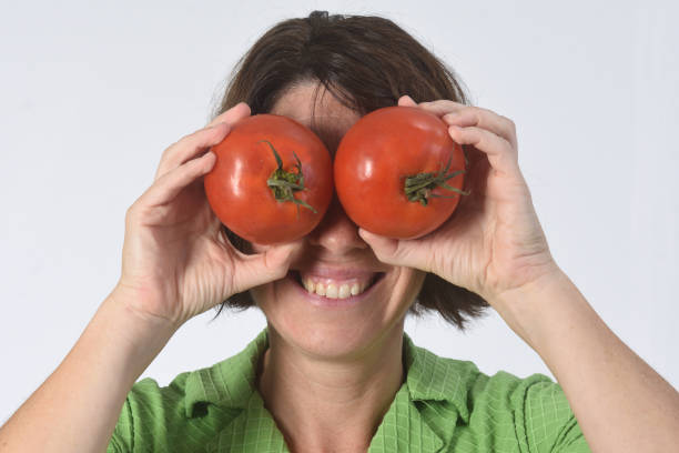 istock woman with tomato on white background 1193669152