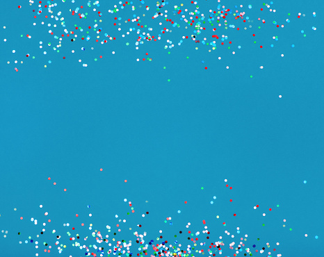 Colorful confetti on blue background with copy space.