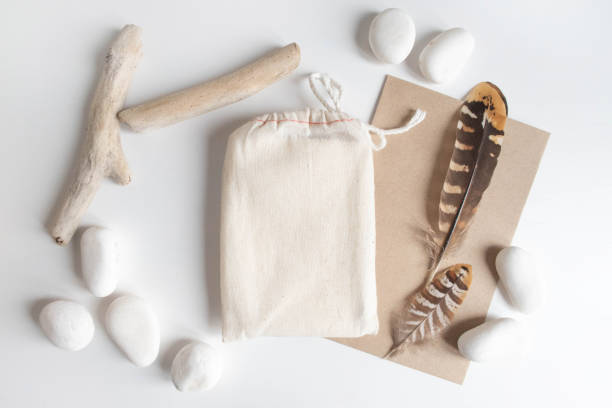 Mock up of cotton bag or pouch and rustic elements, pebble, feathers on white table. Boho design of tarot cards deck pouch on white table with copy space for your image or text stock photo