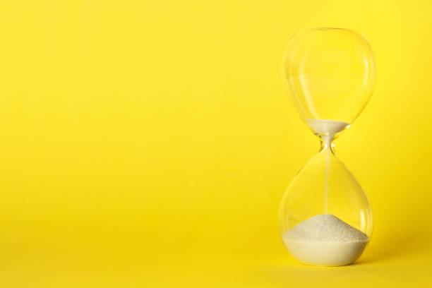 istock An hourglass with oozing sand on a vibrant yellow background with a place for text 1193678668