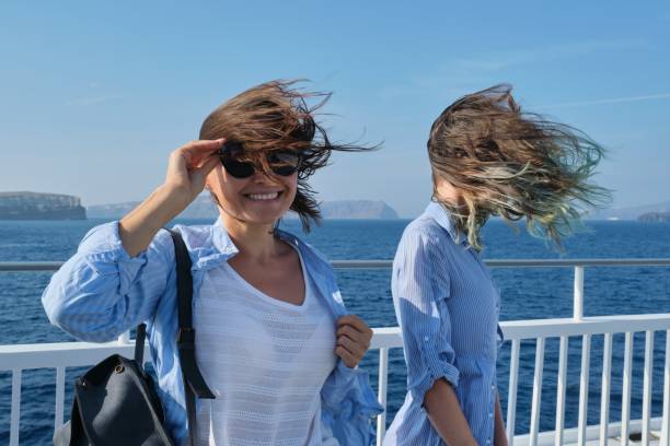 Two women enjoying sea travel on cruise ship, hair flying in the wind Two women enjoying sea travel on cruise ship, hair flying in the wind. ferry deck girls stock pictures, royalty-free photos & images