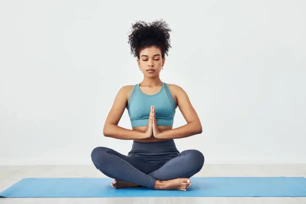 Shot of a fit young woman meditating at home