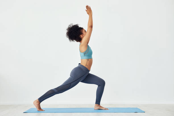 Nothing is more beneficial to the body than movement Shot of a fit young woman doing yoga at home warrior position stock pictures, royalty-free photos & images
