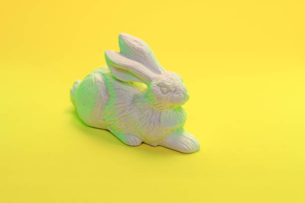 istock White rabbit hare toy in neon light on yellow background. Easter greeting card concept in trendy minimal style, copy space 1193686301