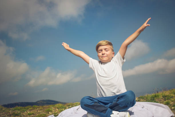 Feeling the nature. Carefree boy with arms outstretched enjoying in sunlight on a meadow. Copy space. mindfulness children stock pictures, royalty-free photos & images