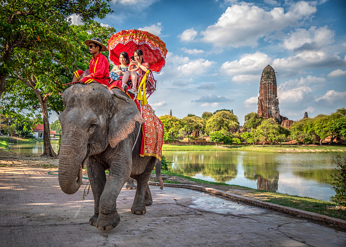 September 11, 2019 - Ayutthaya, Thailand: Tourists on an elephant ride tour in front of Wat Phra Ram in Ayutthaya historical Park, Thailand