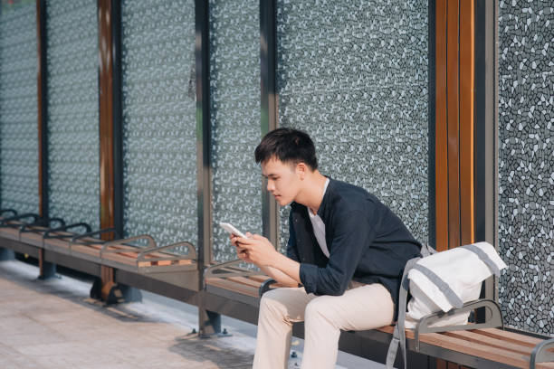 istock Young handsome asian man using mobile phone while waiting in bus stop 1193692734
