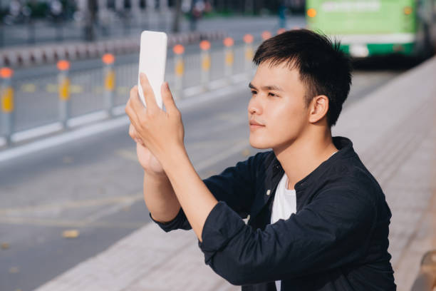 istock Young asian man takes a picture while waiting the bus 1193692825