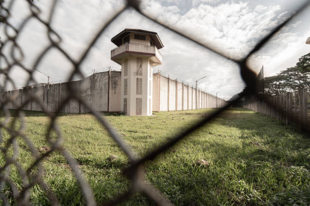 prison with iron fences.prison or jail is a building where people are forced to live if their freedom has been taken away.prison is the building use for punishment prisoner. - confined space safety danger sign imagens e fotografias de stock