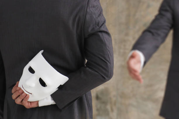 hombre de negocios sosteniendo máscara blanca en su mano deshonesto acuerdo tramposo. fingir y traicionar el concepto de asociación empresarial - maldad fotografías e imágenes de stock