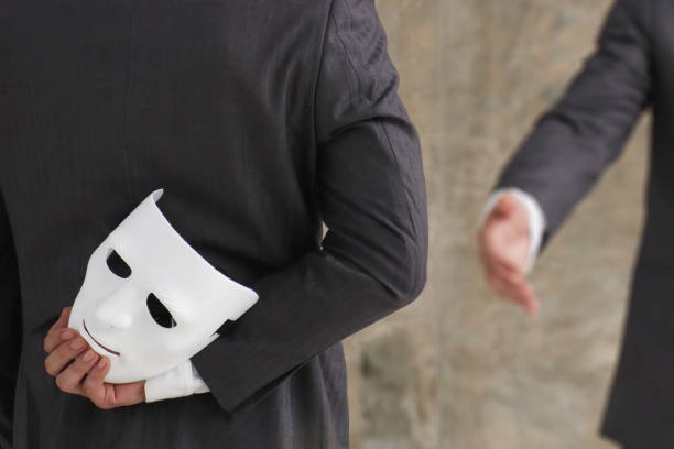 biznesmen trzymający białą maskę w ręku nieuczciwą umowę o oszustwie. udawanie i zdradzanie koncepcji partnerstwa biznesowego - zło zdjęcia i obrazy z banku zdjęć
