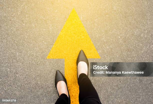 Feet And Arrows On Road Background In Starting Line Beginning Idea Top View Business Woman In Black Shoes On Pathway With Yellow Direction Arrow Symbol Moving Forward New Start And Success Stock Photo - Download Image Now