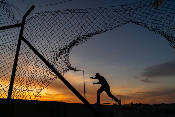 istock Refugee man running behind fence, 1193696176