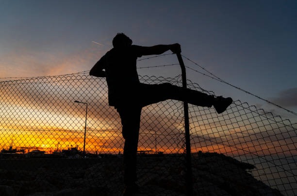 istock Refugee man running behind fence, 1193697355