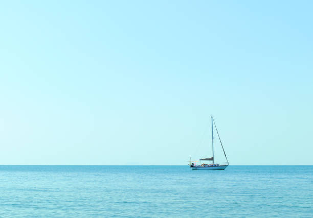 Lonely boat in vast sea under blue sky, copy space composition.
