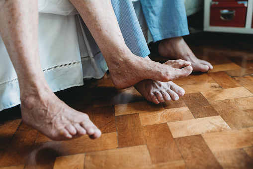 the old grandmother's feet are washed in a plastic bowl with water and soap on the black floor, towels were brought, the old grandmother washes her feet in a bowl on the floor, feet were washed