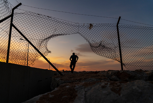 Hombre refugiado corriendo detrás de la cerca, photo