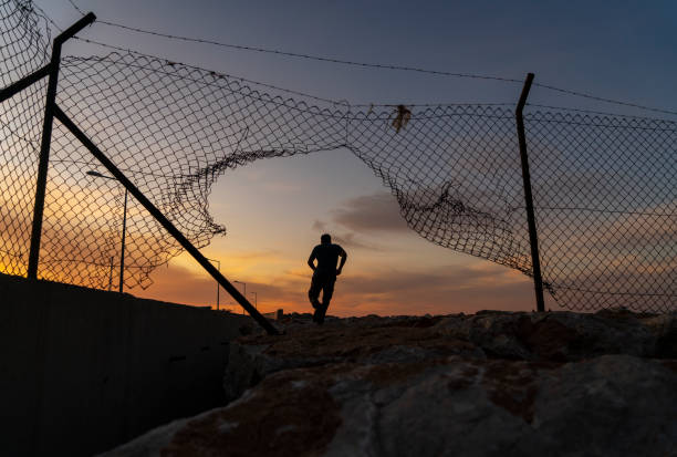 Refugee man running behind fence, Refugee man running behind fence, syria stock pictures, royalty-free photos & images