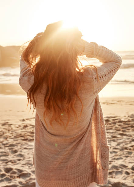 Rearview shot of a young woman spending some time at the beach